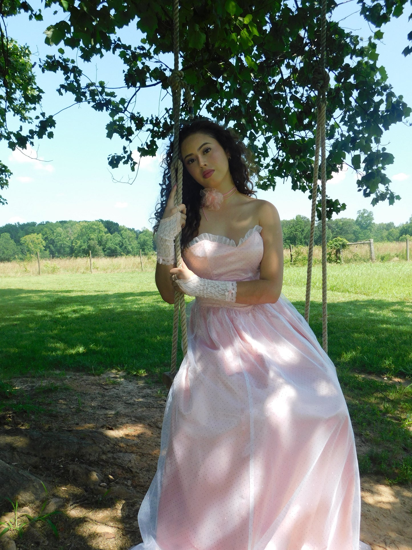 Lace gloves and pink vintage prom dress with tulle skirt, modeled outdoors under trees with dappled sunlight.