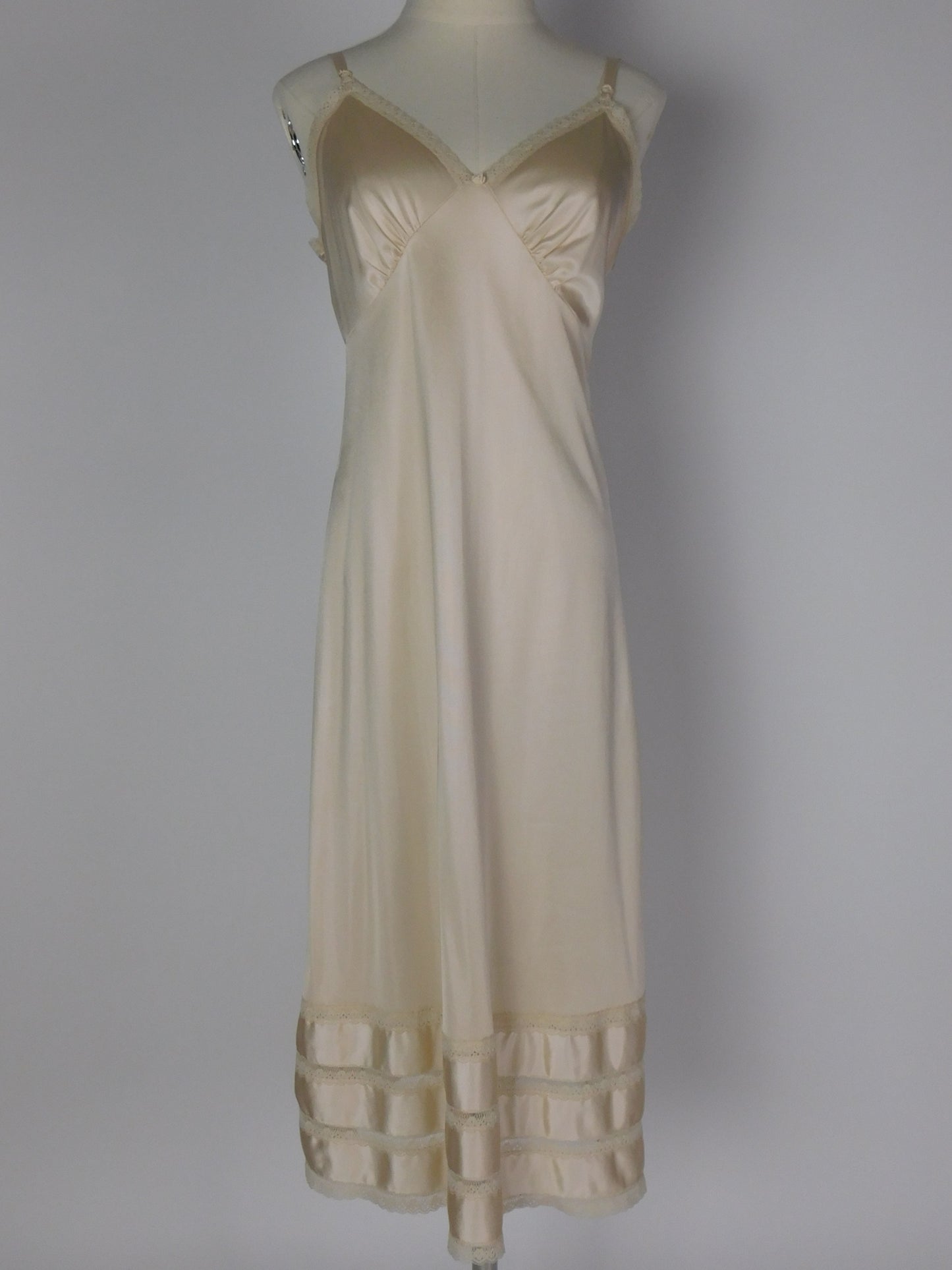 Full front view of 1990s ivory satin slip dress with lace trim, V neckline and silky bias cut on mannequin against neutral backdrop