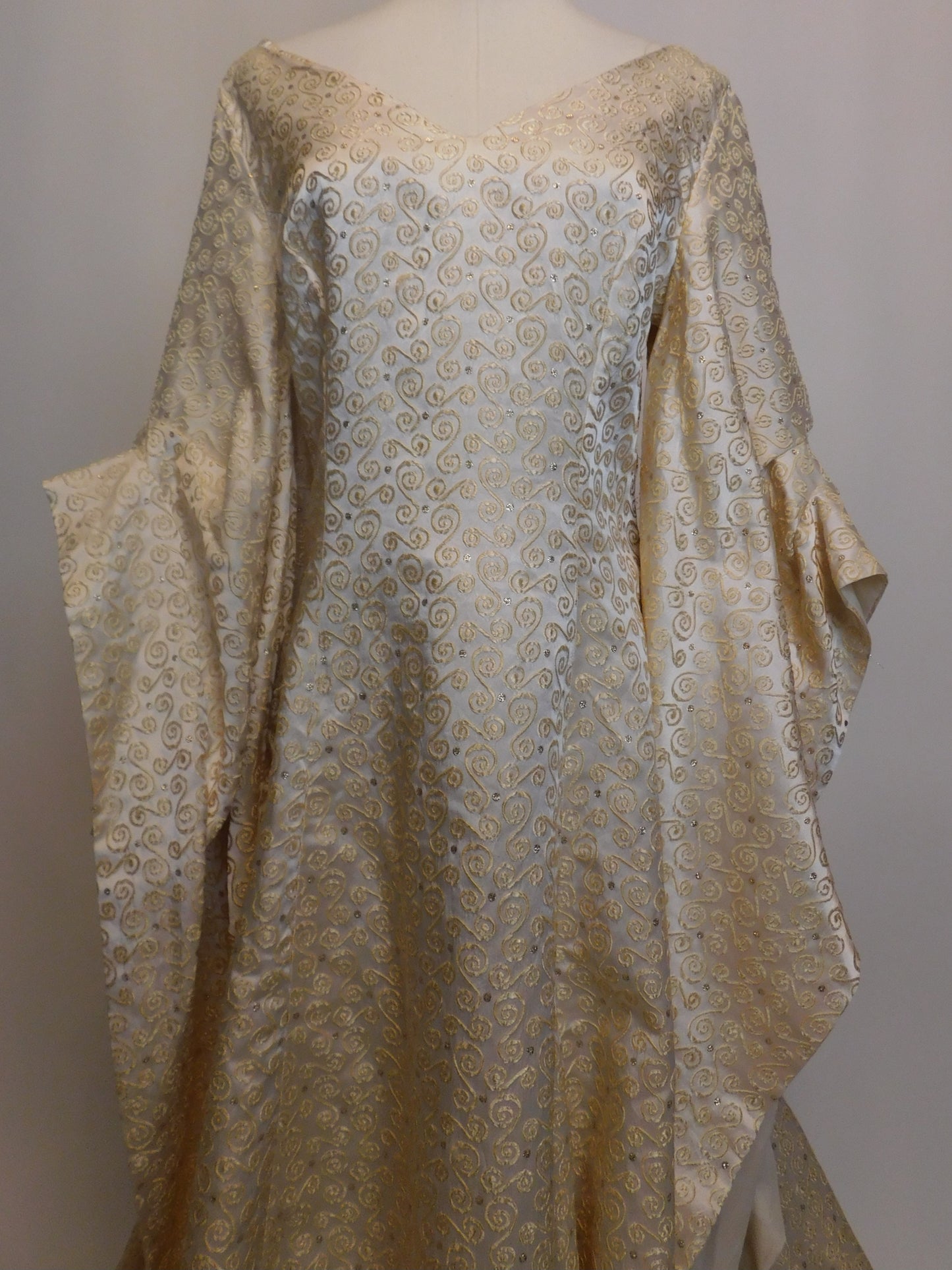 Close-up of 1930s Spanish silk gown showing V-neckline and intricate gold embroidery in swirling patterns.