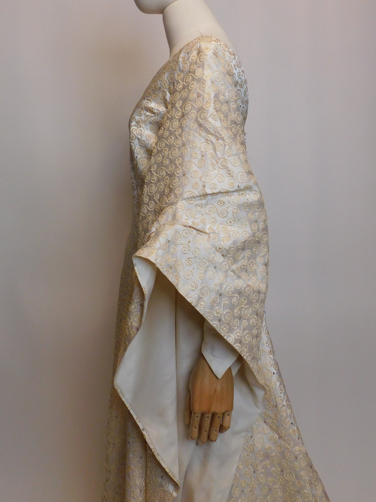 Close-up side view of the 1930s Spanish silk gown sleeve on a mannequin, showcasing the rich brocade pattern and voluminous draping. The cream satin lining of the sleeve is softly folded to highlight craftsmanship.