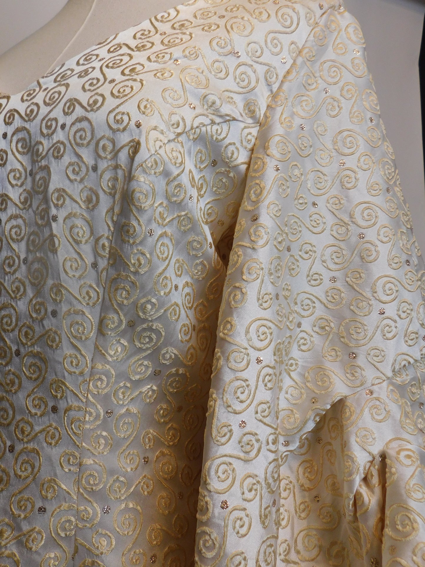 Detailed view of the silk brocade on the 1930s Spanish gown, with golden embroidered spirals and subtle rose gold accents.