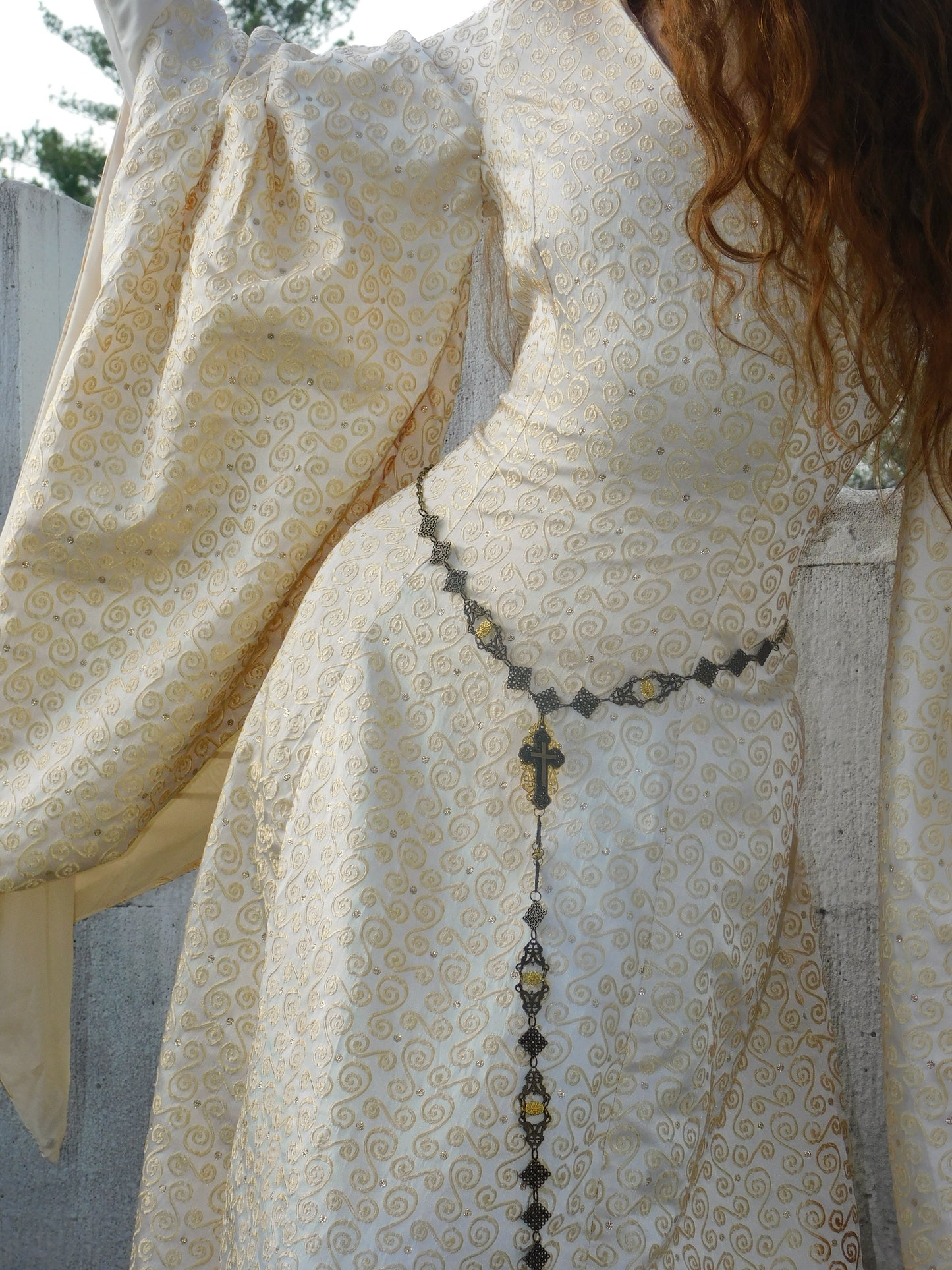 Close-up of 1930s Spanish silk gown featuring delicate swirling gold motifs and a vintage cross belt.