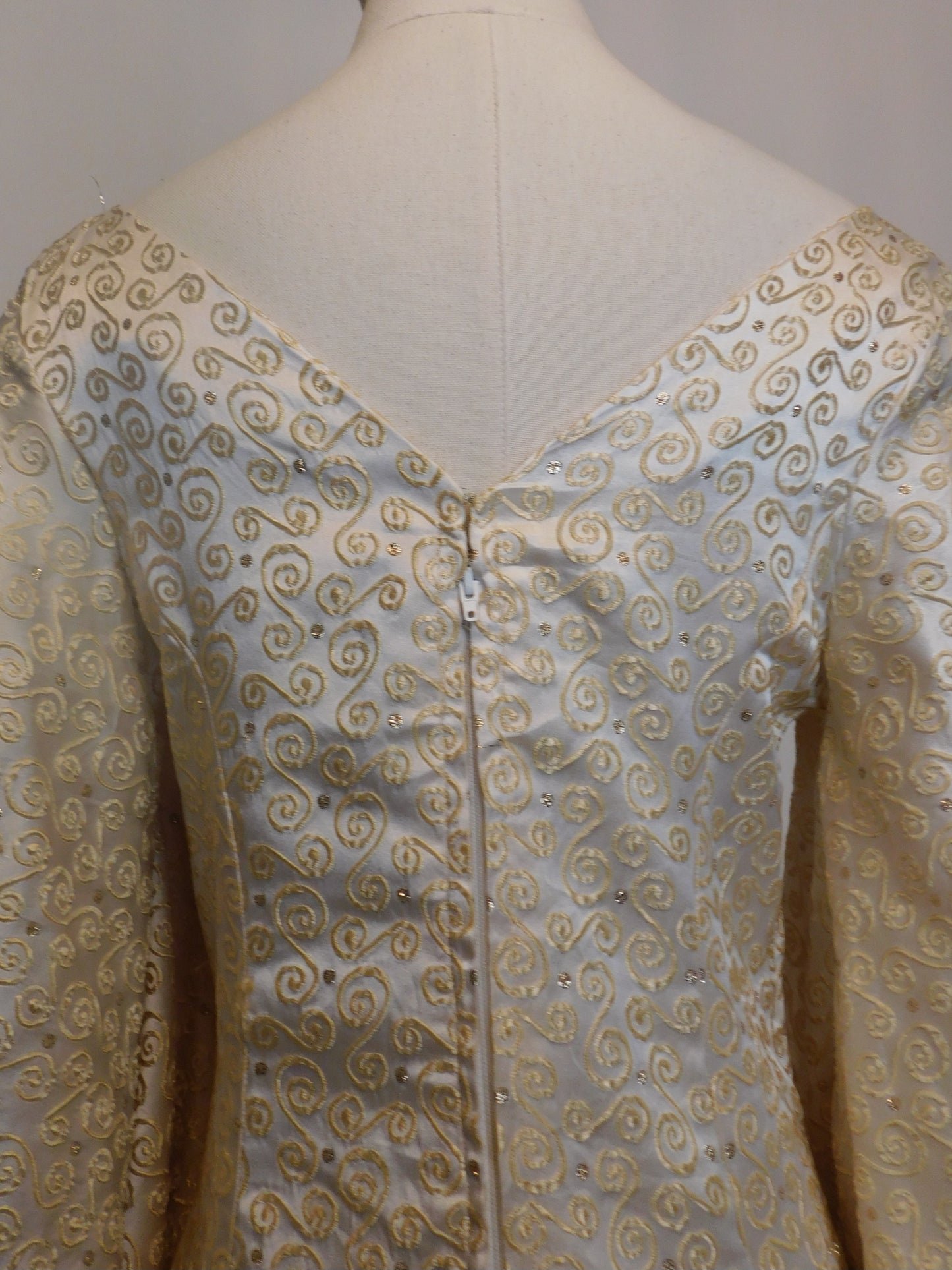 Close-up of the upper back neckline and zipper of the 1930s Spanish brocade gown, showcasing the gold embroidered swirl pattern.