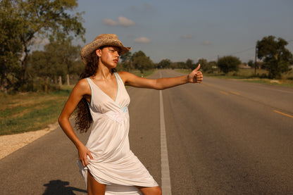 1970s white maxi slip dress with floral appliqué and lace trim styled western, model hitchhiking on sunlit country road