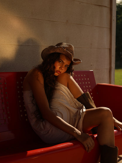 Romantic 1990s ivory satin slip dress with lace detail worn by model on red bench under warm evening light, rustic vibe