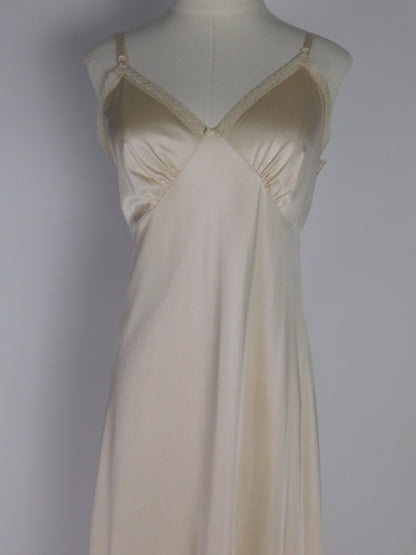 Close-up upper bodice of vintage 1990s ivory satin slip dress showing delicate lace straps and soft draped bustline detail