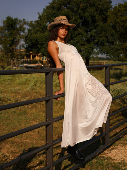 1970s white satin maxi slip dress with pastel floral appliqué, photographed outdoors with rustic countryside background