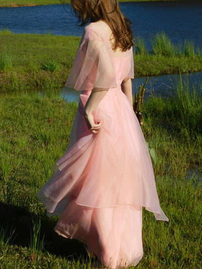 Side profile of model twirling in 1960s sheer pink prom gown – ethereal vintage eveningwear.
