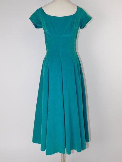 Back view of 1950s teal velvet dress on mannequin, with square neckline and fitted waist