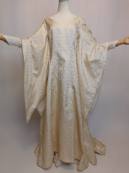 Front view of an antique 1930s Spanish silk gown displayed on a mannequin, with voluminous sleeves fully extended. The gown features intricate golden embroidery and a sweeping hemline.