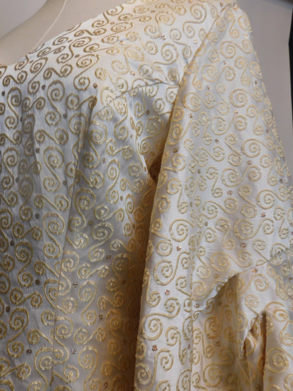 Detailed view of the silk brocade on the 1930s Spanish gown, with golden embroidered spirals and subtle rose gold accents.