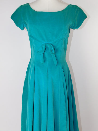 1950s velvet dress front view on mannequin, featuring waist bow and full skirt